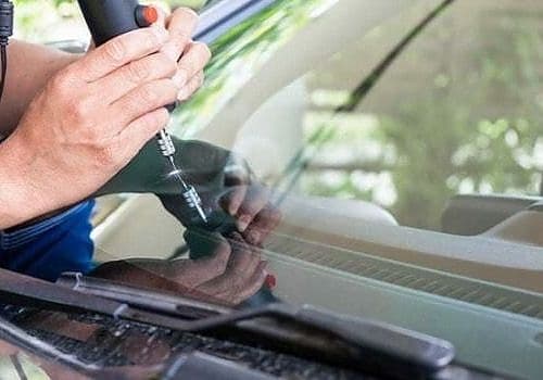 A man using a window cleaner cleans the windshield during auto glass service from Glass Ding.