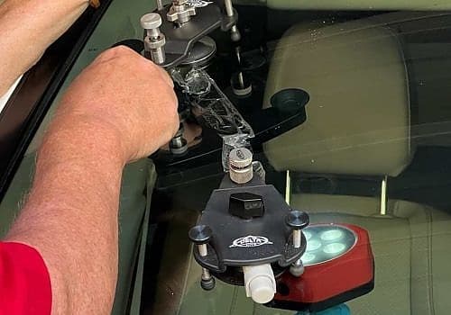 A man is using a tool to fix a car's windshield during a mobile windshield repair by Glass Ding in Oxford, MS.